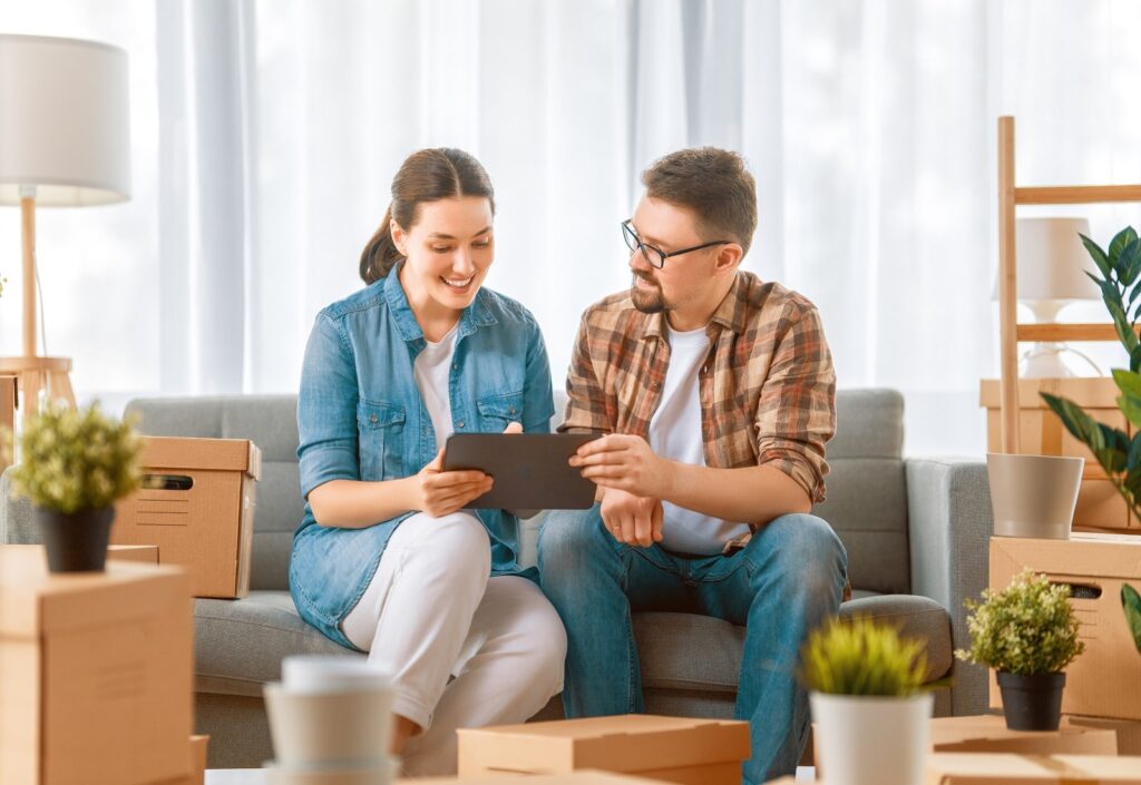 A man and woman sitting on the couch looking at an ipad.
