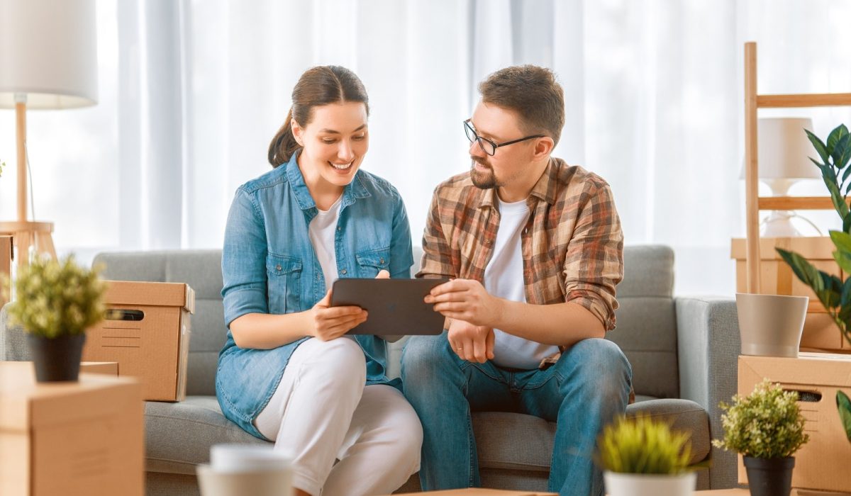 A man and woman sitting on the couch looking at an ipad.